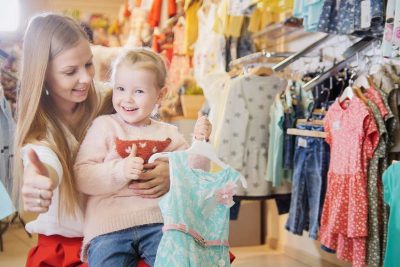 Junge Mutter mit kleiner Tochter beim Shoppen im Secondhand Kinder Wien Shop.