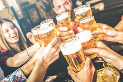 Gruppe von jungen Menschen, die in einem Pub mit Bier anstoßen. Bierlokal Wien.