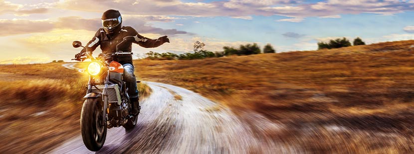 A-Führerschein: Ein Mann sitzt auf einem Motorrad und fährt durch eine wilde Landschaft.