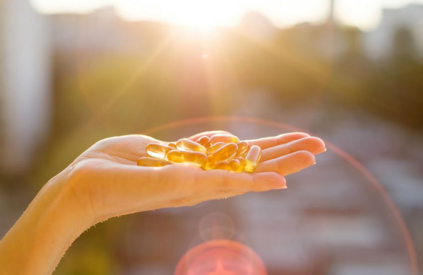 Vitamin D Kapseln liegen auf einer Frauenhand