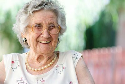 Eine ältere, lachende Frau in einem Pflegeheim.