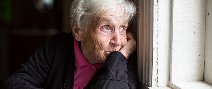 Pflegeheim und Altenheim: Eine alte Frau schaut nachdenklich aus dem Fenster.