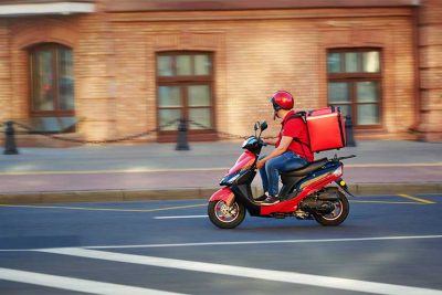 Lieferbote mit Fastfood auf dem Moped. Lieferdienste Lieferservice Österreich.