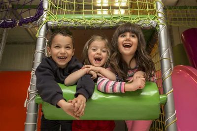 Zwei Mädchen und ein Junge, die Spaß im Indoorspielplatz haben.