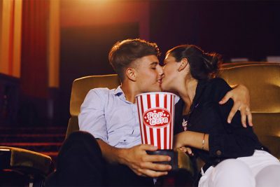 Junges Pärchen, das sich im Kino einen Film anschaut und sich küsst. Kinos Wien.