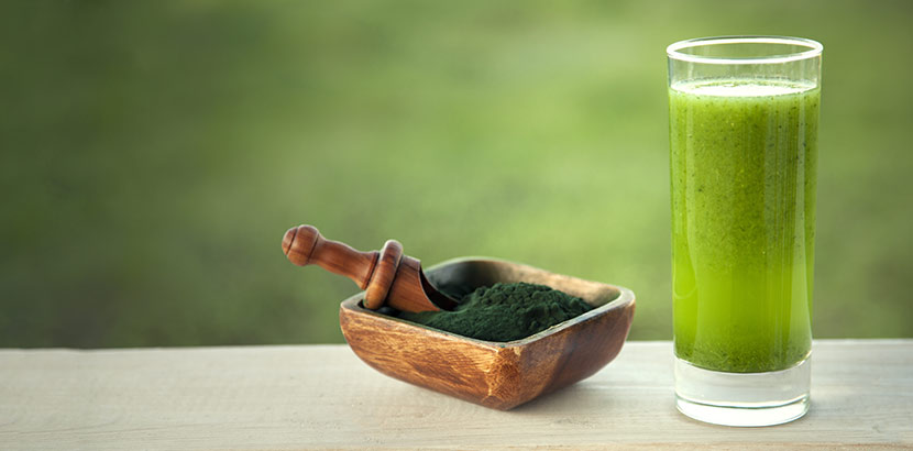 Spirulina Pulver neben einem Glas mit Spirulina Smoothie, einem Rezept mit Superfood.