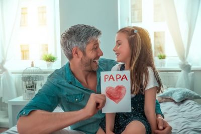 Kleines Mädchen, das ein Geschenk für Papa übergibt.