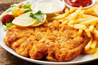 Schnitzel Wien: Ein großes Wiener Schnitzel mit Pommes, Zitrone und Ketschup.