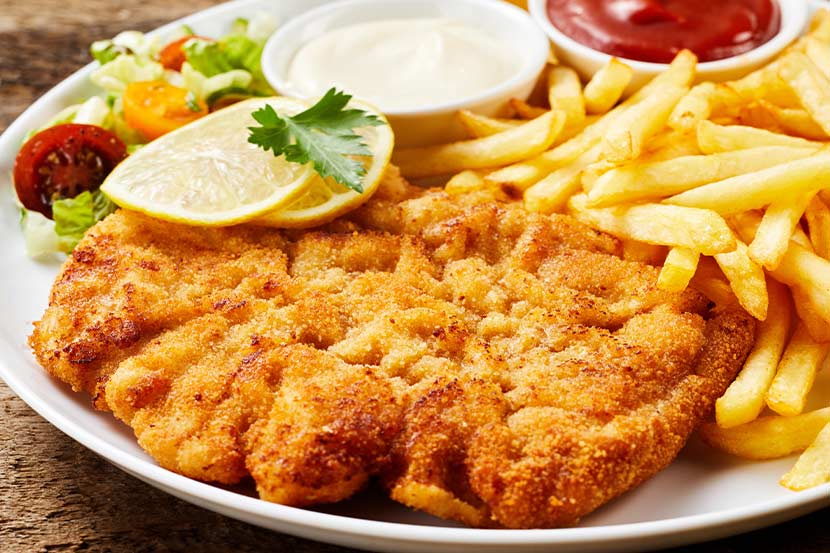 Schnitzel Wien: Ein großes Wiener Schnitzel mit Pommes, Zitrone und Ketschup.