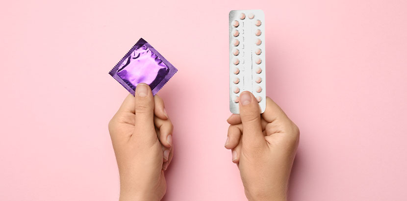 Zwei Frauenhände, eine hält ein Kondom, die andere die Anti-Baby-Pille. Verhütungsmittel Überblick.