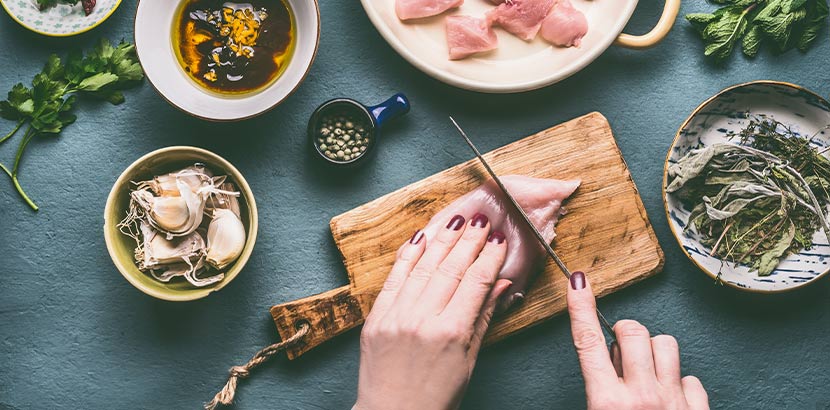 Frauenhände, die Fleisch schneiden. Ernährung gegen starke Regelschmerzen.