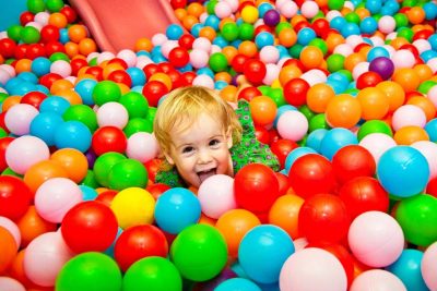 Kleines blondes Mädchen im Bällebad im Indoorspielplatz.