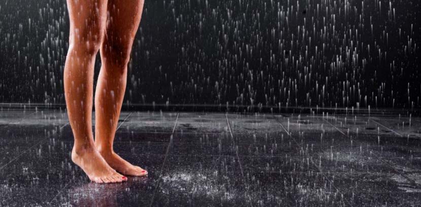 Junge schöne Frau nackt unter der Regendusche.