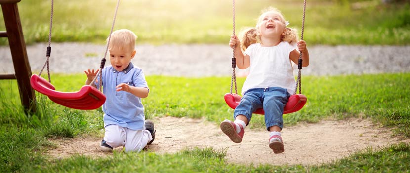 Gartenmöbel für Kinder: Zwei Kinder spielen auf einer Kinderschaukel aus Holz und Kunststoff.