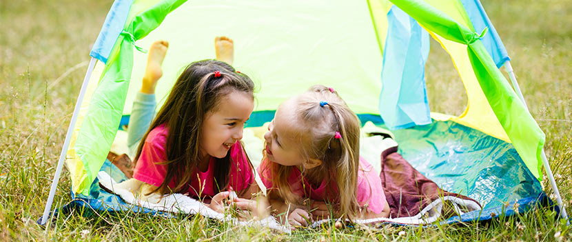 Gartenmöbel für Kinder: zwei kleine Mädchen spielen in einem Kinderzelt im Garten