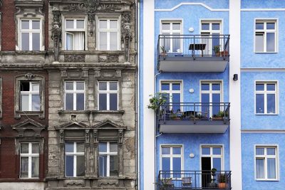 Fassaden von zwei gleichen Häusern, das eine saniert, das andere nicht. Altbausanierung Förderung Sanierungsscheck 2021.