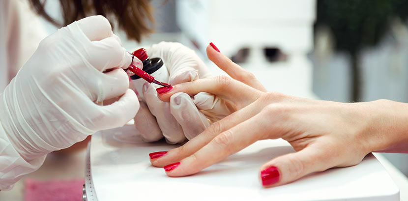 Eine Nageldesignerin kreiert bei der Maniküre rote Shellac Nägel