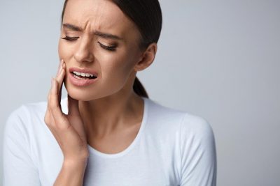 Eine Frau mit Schmerzen am Zahn vor der Behandlung möglicher Ursachen.
