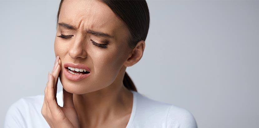 Eine Frau mit Schmerzen am Zahn vor der Behandlung möglicher Ursachen.