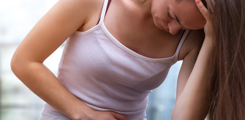 Eine Frau mit Blasenentzündung hält sich den Bauch vor Schmerzen.