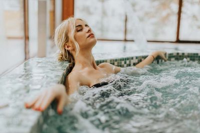 Junge blonde Frau, die sich in einem Whirlpool entspannt. Day Spa Wien.