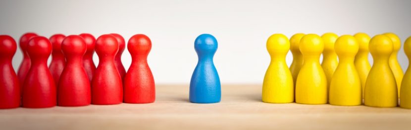 Blaue Figur, die zwischen einer Gruppe von gelben und einer Gruppe von roten Figuren steht und dadurch das Konzept einer Mediation versinnbildlicht.