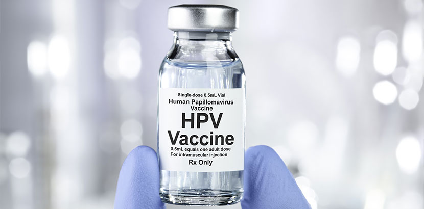 Kleine Flasche mit HPV Impfstoff, die von einem Arzt hochgehalten wird. HPV Impfung.