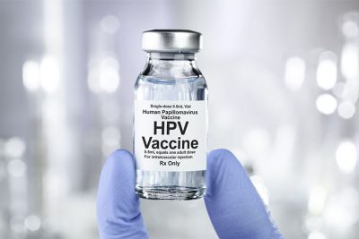 Kleine Flasche mit HPV Impfstoff, die von einem Arzt hochgehalten wird. HPV Impfung.