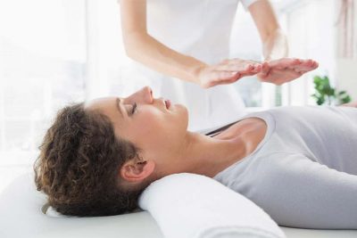 Junge Frau bei der Reiki Behandlung, auf dem Rücken liegend.