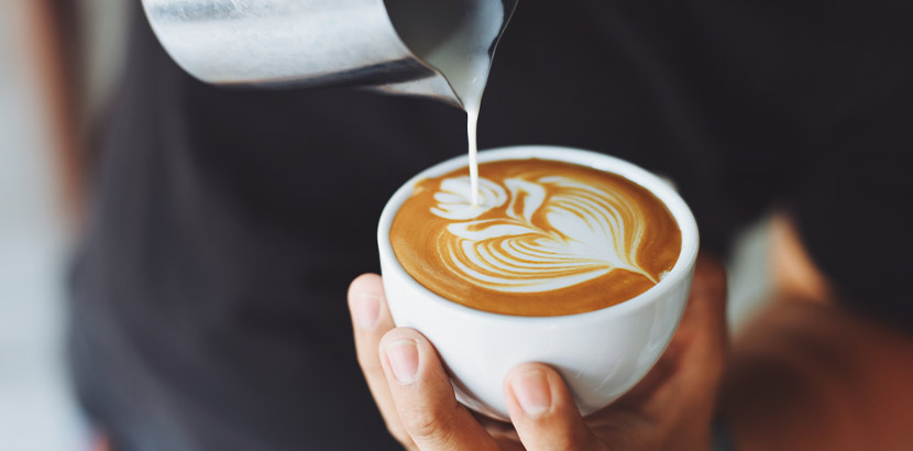 Kaffeehaus Linz: Eine Person bereitet einen Milchkaffee zu