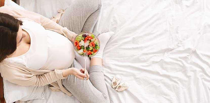 schwangere Frau hält Salat Schüssel in der Hand