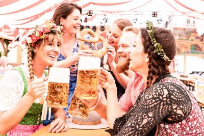 Gruppe von Frauen und Männern, die auf der Wiener Wiesn 2021 mit Biergläsern anstoßen.