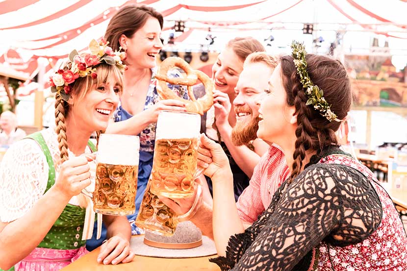 Gruppe von Frauen und Männern, die auf der Wiener Wiesn 2021 mit Biergläsern anstoßen.