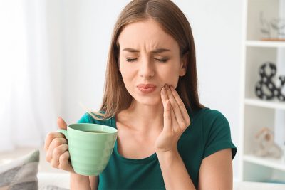 Junge Frau mit schmerzempfindlichen Zähnen, die ihren Zahnschmelz aufbauen muss.