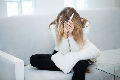 Junge verzweifelte Frau mit positivem Schwangerschaftstest. Abtreibung Wien Kosten.