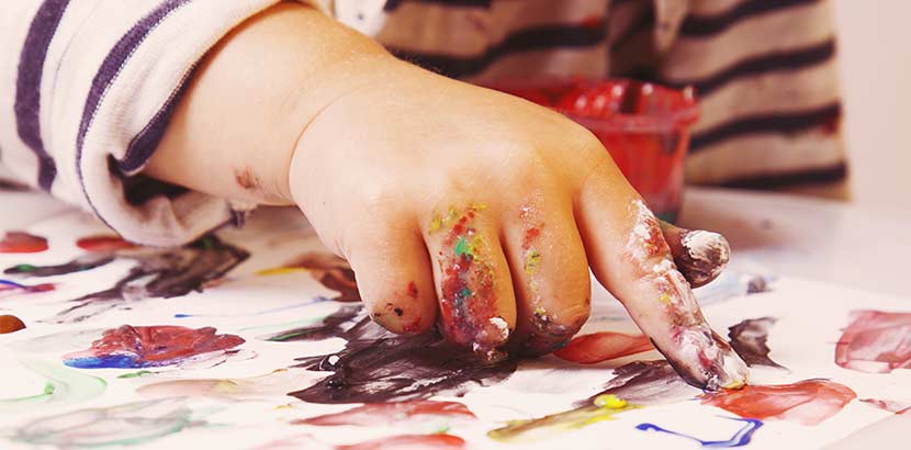 Ergotherapie bei Kindern - Kind malt auf Papier mit Farben