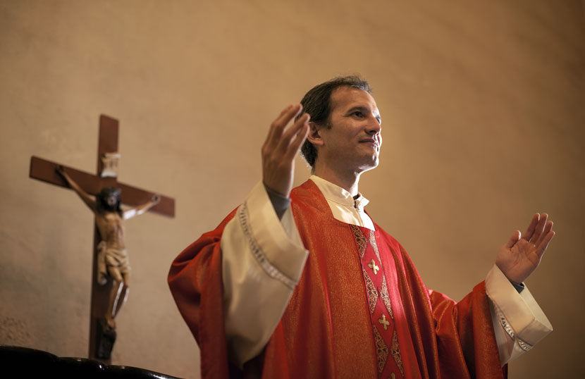 Ein katholischer Pfarrer predigt vor einem Kreuz.