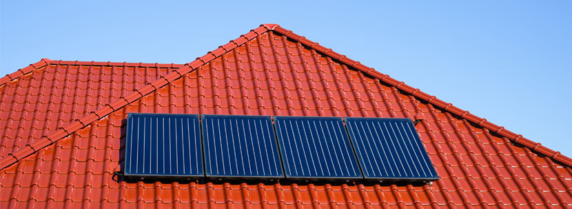 Sonnenkollektoren hängen auf einem roten Hausdach