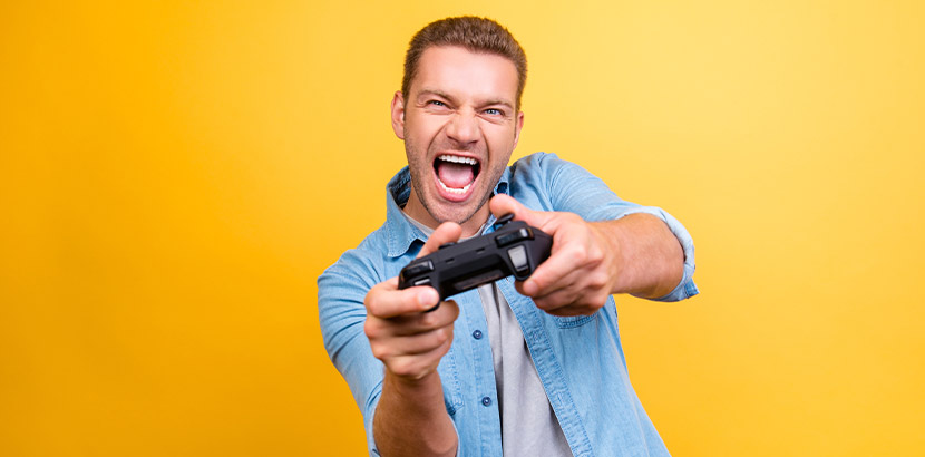 Mann mit blauem Hemd und einem Controller vor gelber Wand. Außergewöhnliche Geschenke.