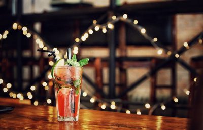 Ein Glas mit einem roten Cocktail auf einer Theke. Cocktailbar Linz