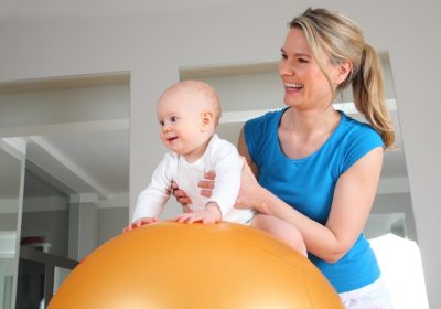 Junge blonde Osteopathin, die mit einem Baby arbeitet. Osteopathie Linz.