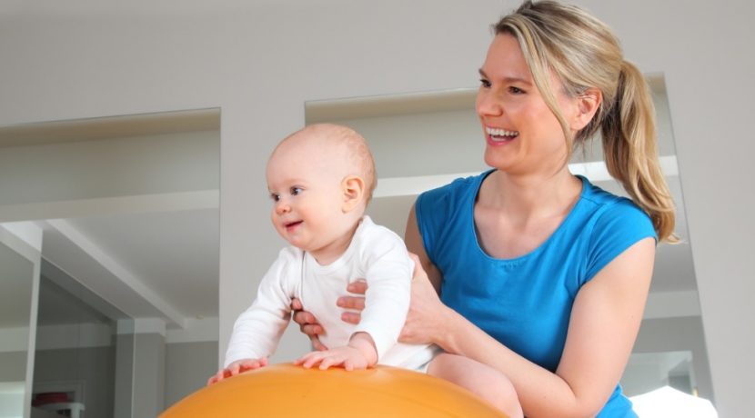 Junge blonde Osteopathin, die mit einem Baby arbeitet. Osteopathie Linz.