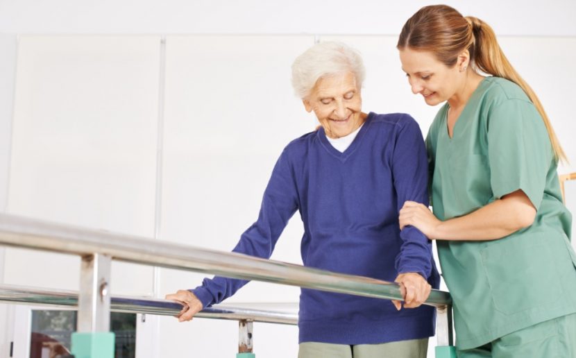 Junge blonde Physiotherapeutin mit einer älteren weißhaarigen Patientin in der Reha Maßnahme. Physiotherapie Linz.