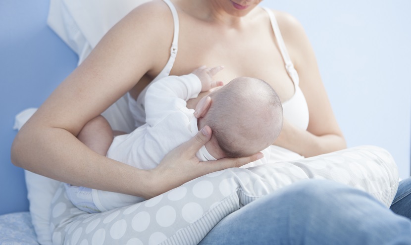Baby wird von Mutter gestillt mit Hilfe eines Stillkissens