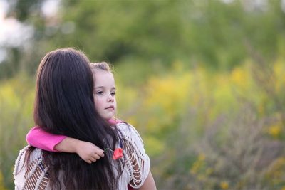 Kleines Mädchen, das von ihrer Mutter im Arm gehalten wird. Bestattungskosten, Begräbniskosten.