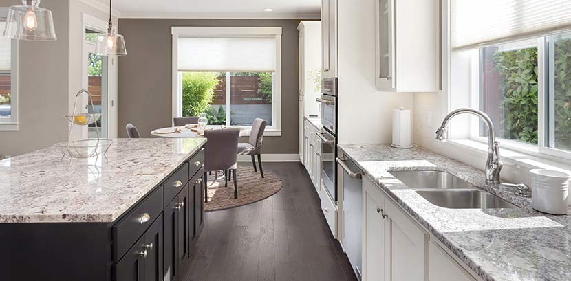 Eine moderne, helle Küche mit einer Kücheninsel und Arbeitsplatte aus Granit.