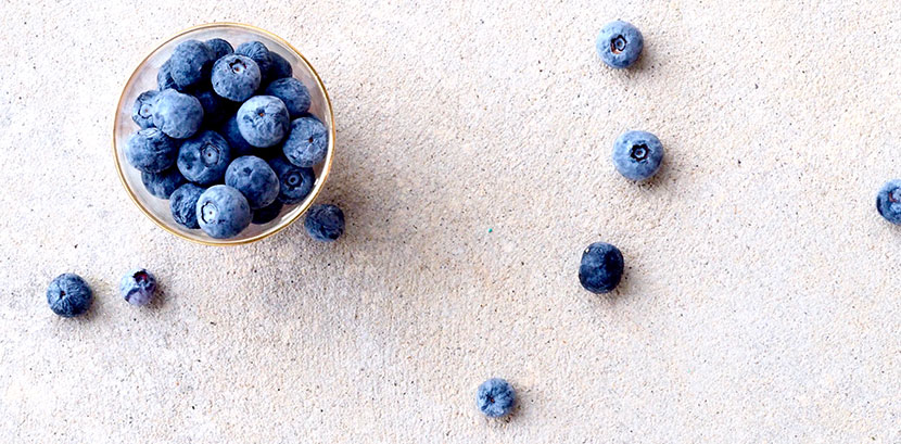 Blaubeeren / Heidelbeeren in einem Schälchen auf einem Tisch: Sie sollen durch ihre Anitoxidantien Sonnenallergie vorbeugen.