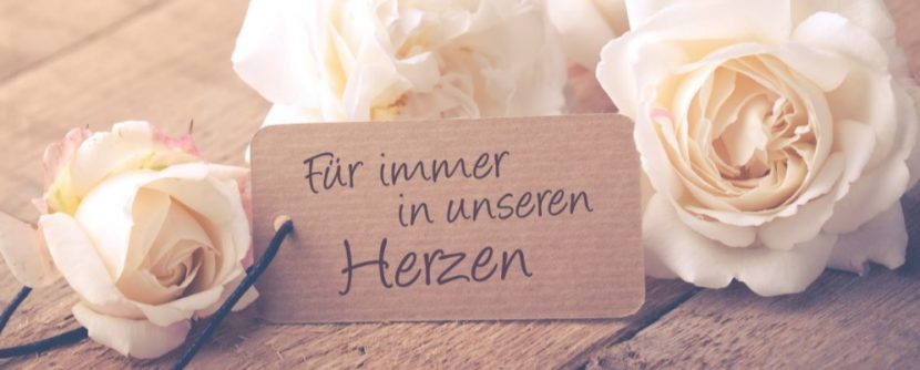 Vier weiße Rosen verteilt um einen Schild, das sich auf einen Todesfall bezieht. Todesfall Checkliste Österreich.