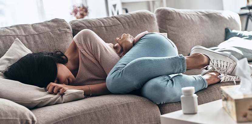 Junge dunkelhaarige Frau, die weinend auf dem Sofa liegt. Trauerbegleitung Wien.