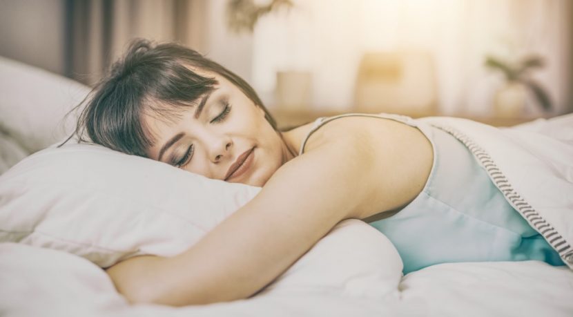 Hübsche junge Frau mit dunklen Haaren, die in den frühen Morgenstunden in ihrem Bett schläft. Wasserbetten Preise Wien.